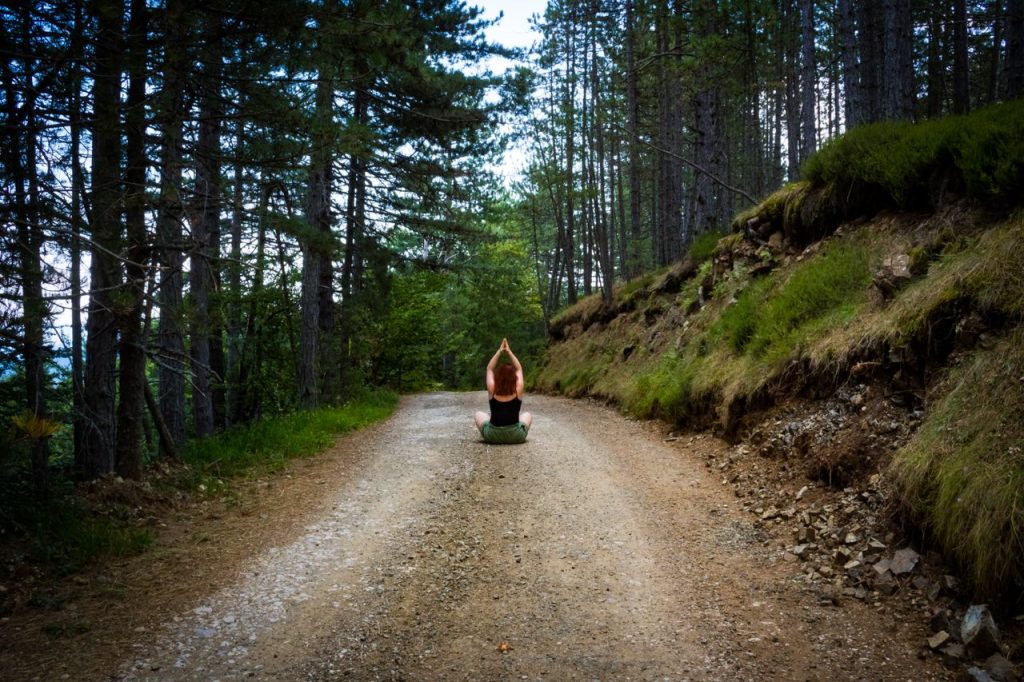 A person meditating on a forest path, embracing natures tranquility in summer.